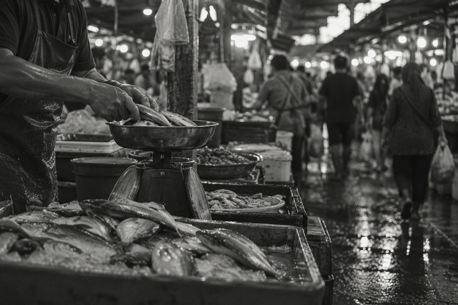 Gambar hitam putih lorong pasar ikan yang sibuk dan basah, tangan penjual di atas dacing, bakul ikan di depan